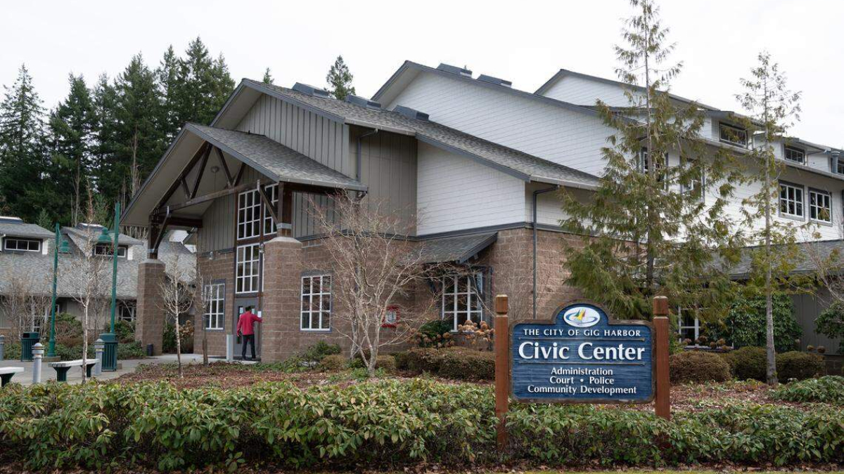 Municipal Civic Center building with stone columns and a blue 'Civic Center' sign in front listing Administration, Court, Police, and Community Development in Gig Harbor.