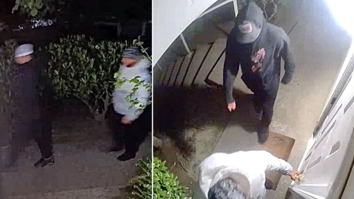 Two masked men standing outside a house at night; one in a gray beanie and white jacket, the other in dark clothing.