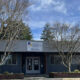 Front view of Sound Christian Academy building with a banner above the entrance, two leafless trees flanking the doors, and an American flag on a tall pole to the right.