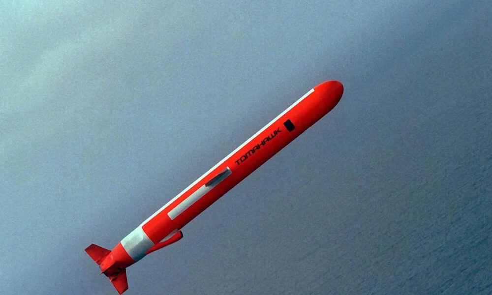 Red rocket streaking upward diagonally over a blue sea horizon.