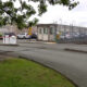 Railroad crossing entrance to a fenced industrial lot with a guard booth and parked cars nearby