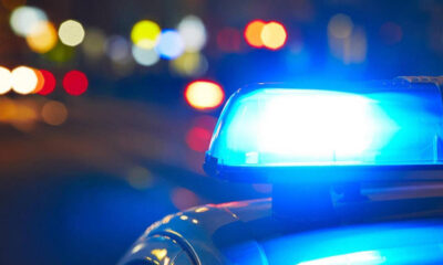 Blue flashing police siren on top of a car with blurred city lights at night (bokeh).