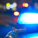 Blue flashing police siren on top of a car with blurred city lights at night (bokeh).