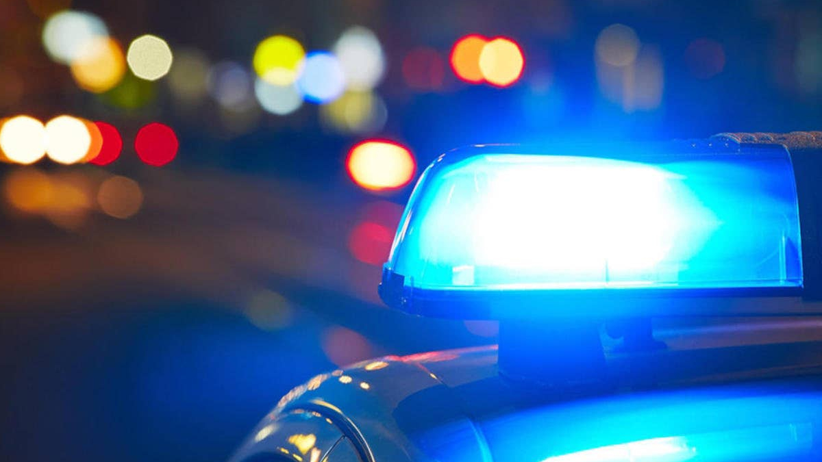 Blue flashing police siren on top of a car with blurred city lights at night (bokeh).