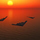 Three stealth bomber aircraft fly in a loose triangle over an orange sunset-lit ocean.