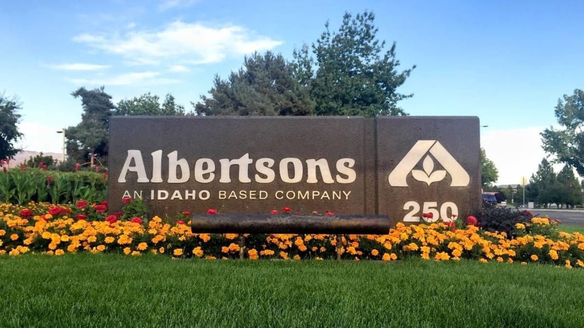 Albertsons sign at entrance with flower bed, Idaho-based company and 250th anniversary logo visible