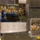 Top-down view of a waste-sorting facility with multiple conveyor belts and heaps of mixed recyclables and trash on a metal chute system.