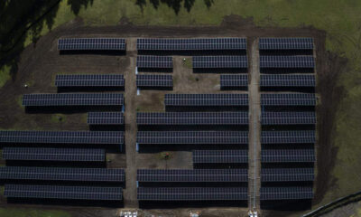 Aerial view of a solar farm with rows of solar panels on a grassy field.