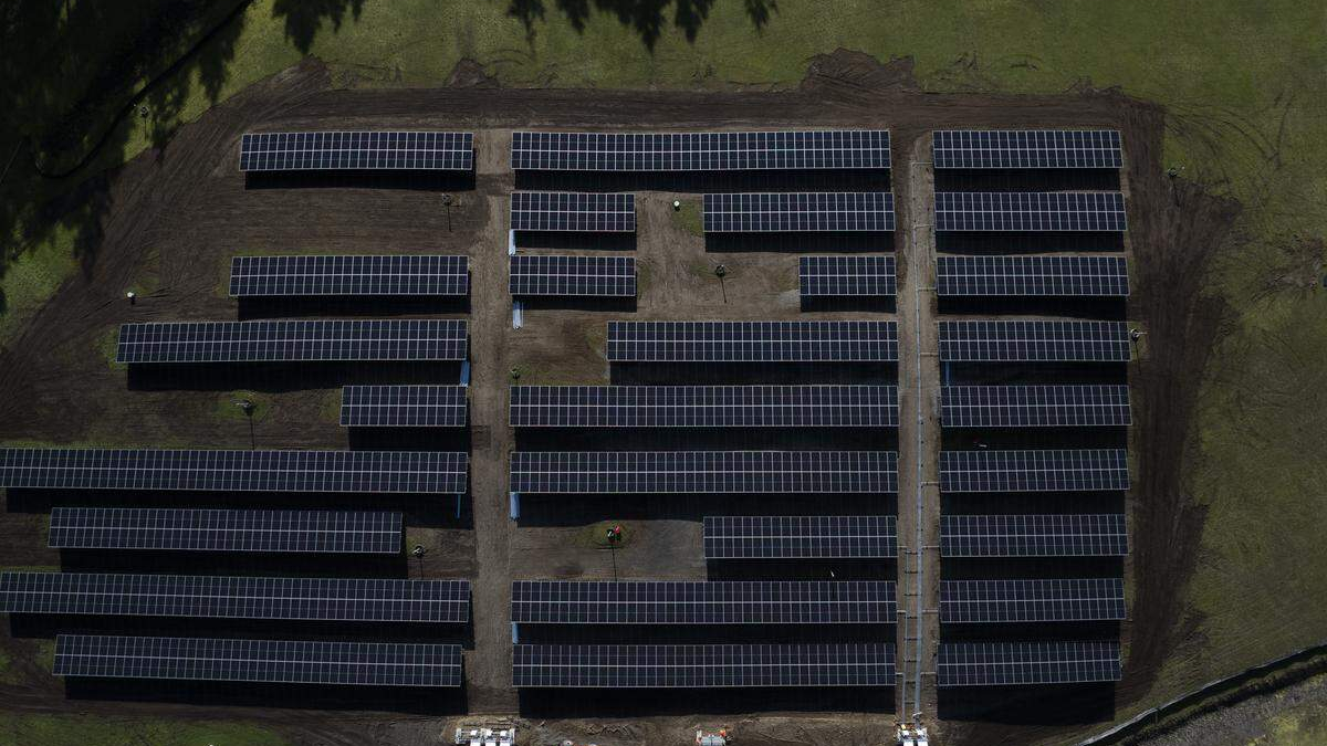 Aerial view of a solar farm with rows of solar panels on a grassy field.