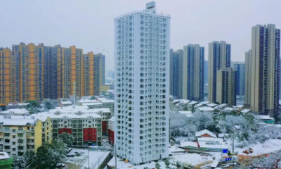 Snow-covered cityscape with a tall white residential tower surrounded by colorful high-rrise buildings.
