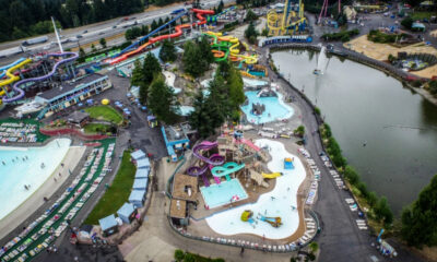 Aerial view of a bustling water park with colorful twisting slides, pools, and a surrounding lake.