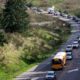 Traffic on a curved, two-lane road with a yellow school bus leading the line amid trees and green hills.”