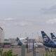 Airplanes with Alaska Airlines tails parked at a gate area of a sunny airport terminal.