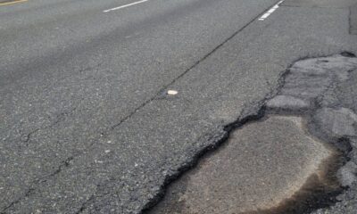 Pothole in a cracked asphalt road near the curb on the right side of the lane boundary gradually expanding into the pavement edge.