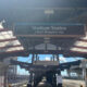 Platform at Stadium Station with a sign reading 'Stadium Station' and 'S Royal Brougham Way', view down the concourse under a glass canopy.