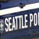 Side view of a Seattle Police Department patrol car with large 'SEATTLE POLICE' lettering and badge logo on the door