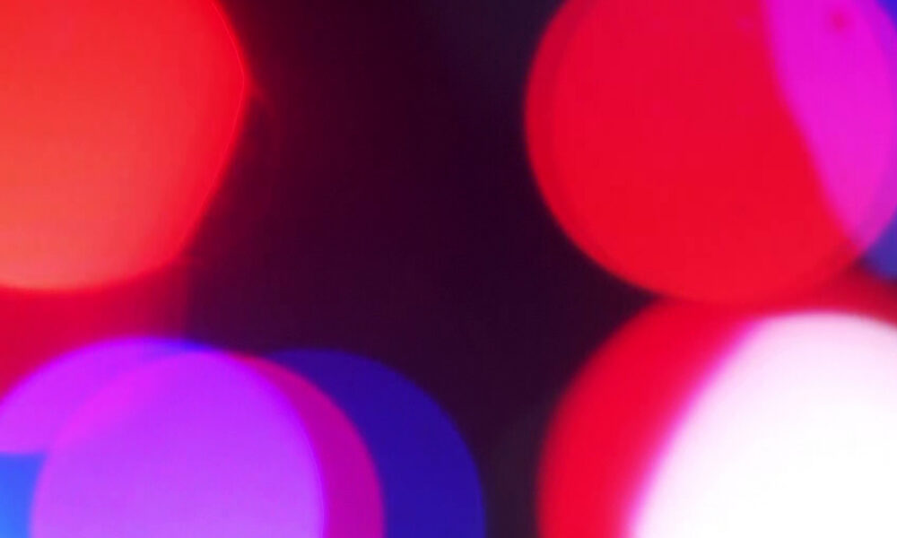 Abstract close-up of colorful bokeh lights in red, pink, and blue against a dark background.