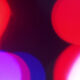 Abstract close-up of colorful bokeh lights in red, pink, and blue against a dark background.