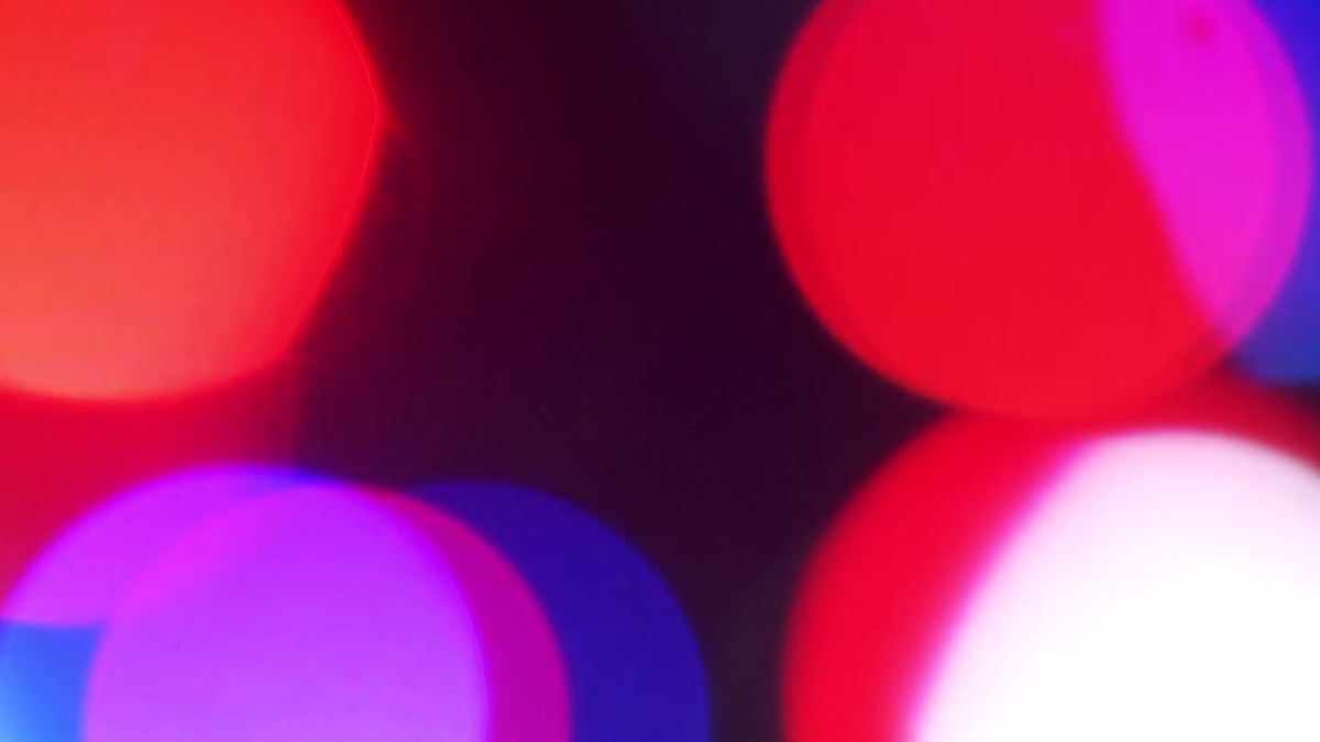 Abstract close-up of colorful bokeh lights in red, pink, and blue against a dark background.