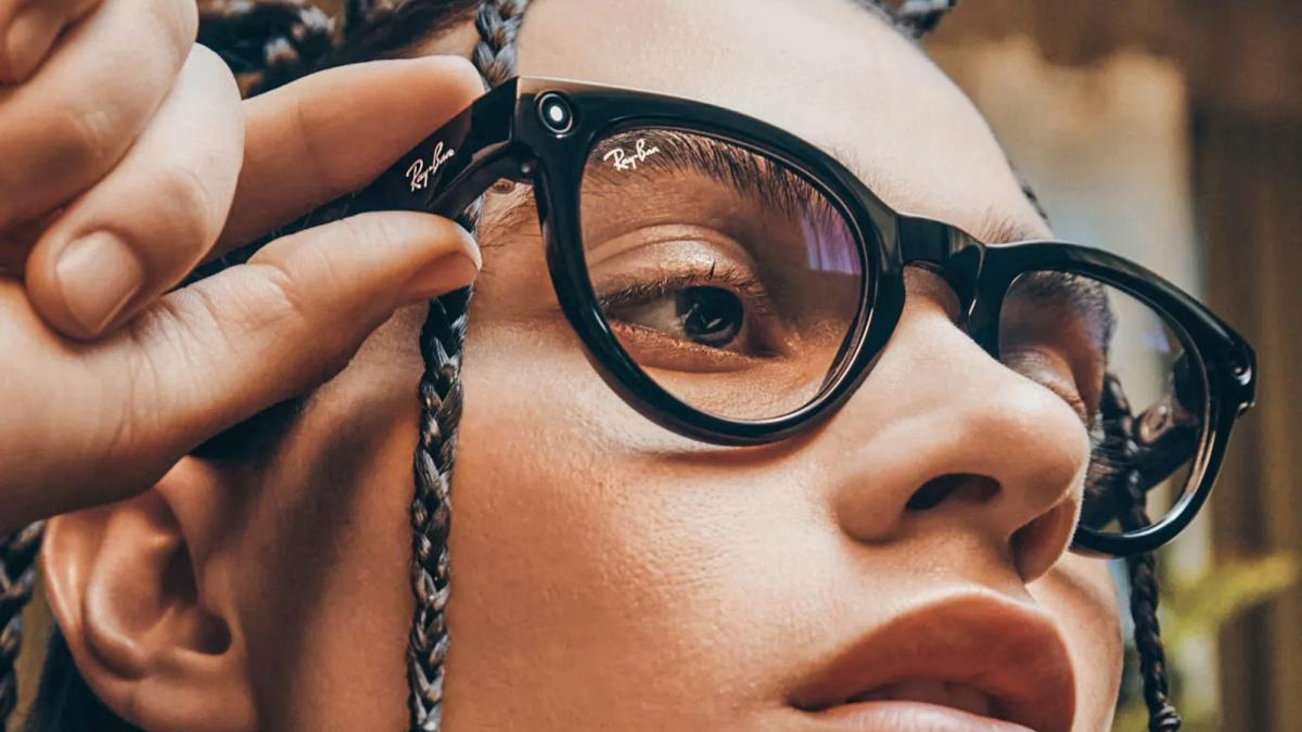 Close-up of a person wearing black Ray‑Ban glasses, adjusting a braided strap near the frame.