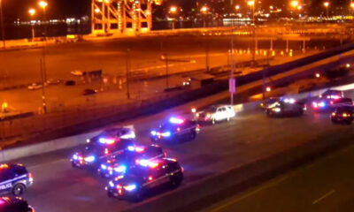Nighttime scene with multiple police cars flashing red and blue lights on a city street near a highway.”