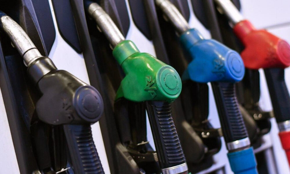 Row of fuel nozzles at a gas pump in black, green, blue, and red colors without focusing on any single one