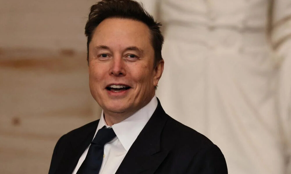 Smiling man in a black suit and white shirt at a formal event, looking at the camera in a portrait shot.