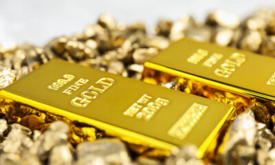 Two shiny gold bars lying on a pile of gold nuggets from a close view.
