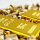 Two shiny gold bars lying on a pile of gold nuggets from a close view.