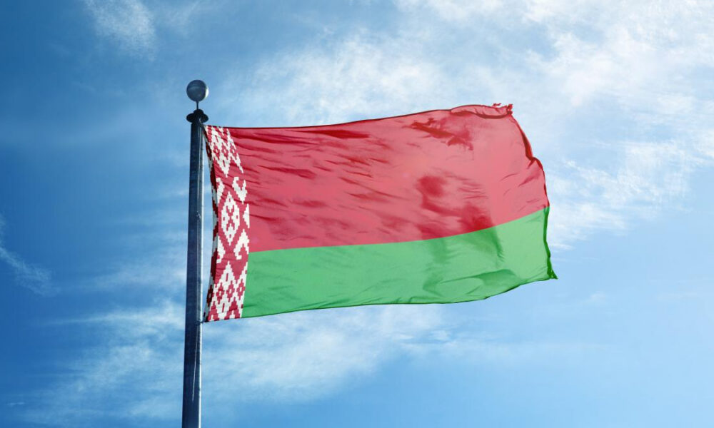 Belarus flag waving on a flagpole against a blue sky with white clouds.