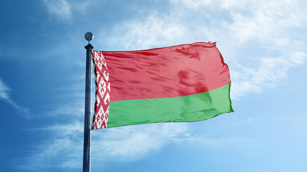 Belarus flag waving on a flagpole against a blue sky with white clouds.