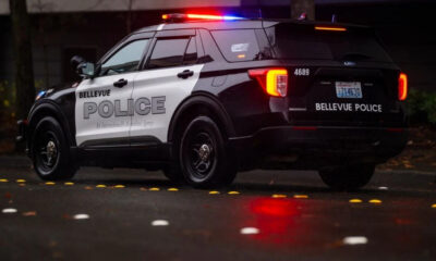 Bellevue Police SUV with red and blue emergency lights on at night on a wet street.