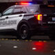 Bellevue Police SUV with red and blue emergency lights on at night on a wet street.