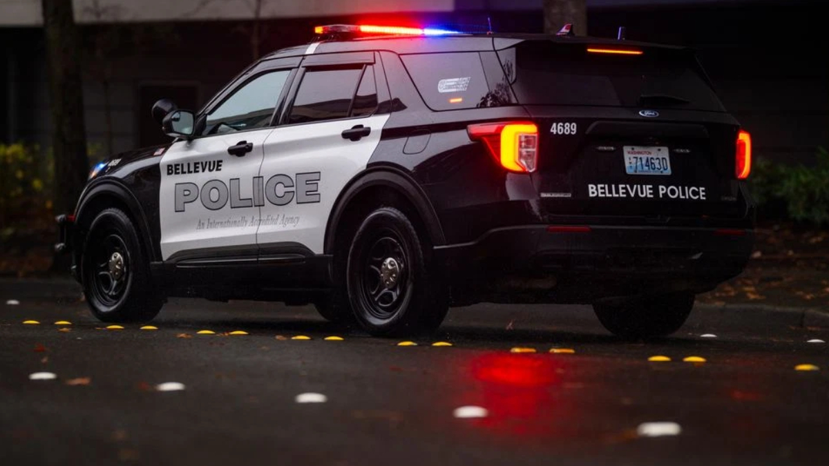 Bellevue Police SUV with red and blue emergency lights on at night on a wet street.
