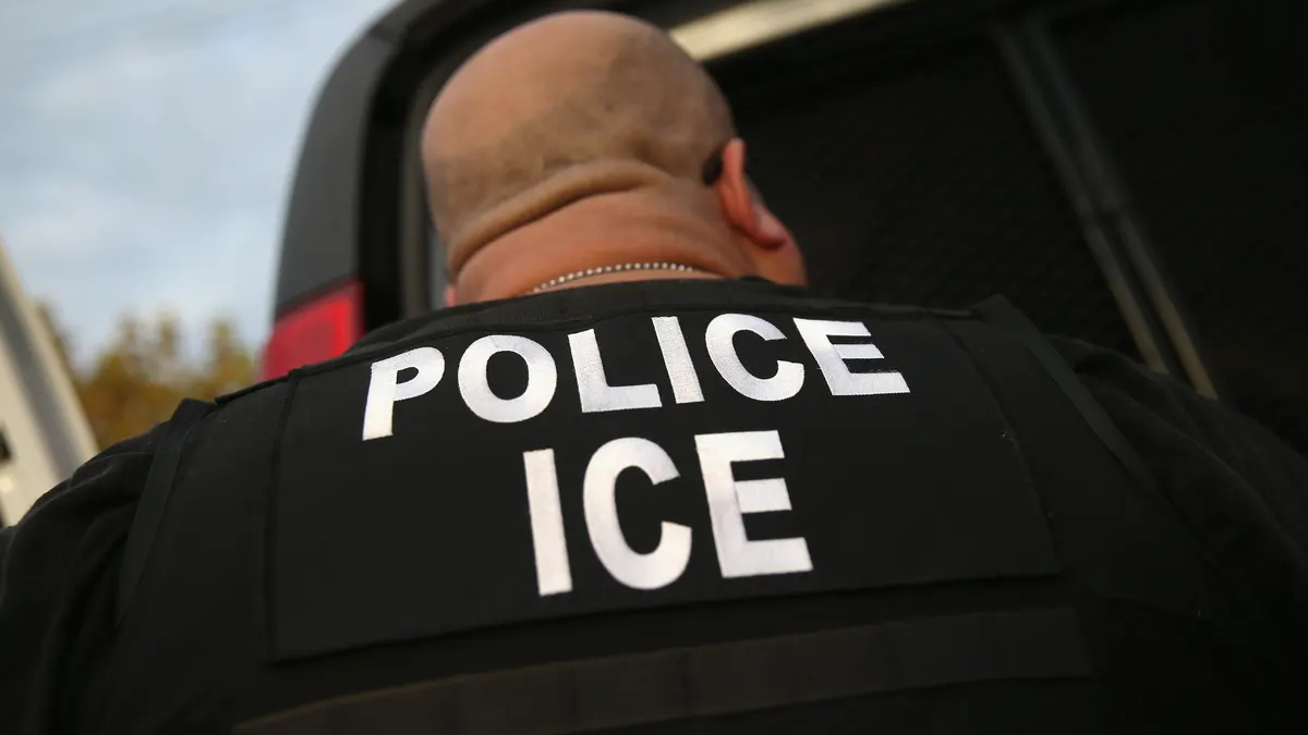 Close-up of a law enforcement officer's vest reading 'POLICE ICE' on the back.