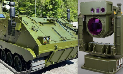 Green armored tracked vehicle beside a large gyrostabilized optical sensor with purple lenses on the right side.