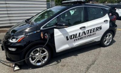 Black-and-white police volunteer car labeled 'Volunteers Everett Police' with a charging cable plugged in.