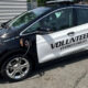 Black-and-white police volunteer car labeled 'Volunteers Everett Police' with a charging cable plugged in.