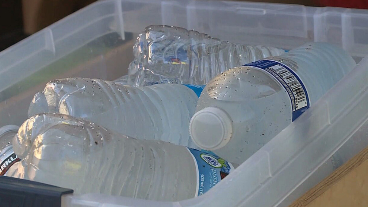 Clear storage bin containing multiple plastic water bottles, some empty or partially full, with condensation on the surfaces.