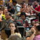 Crowded indoor dining area with people seated at tables, eating and using laptops.