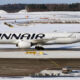 White Finnair passenger jet on a snow-covered airport tarmac, logo prominently displayed on the fuselage.