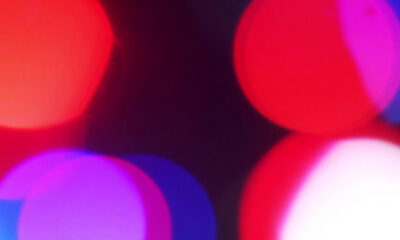 Abstract background of red, pink, and purple bokeh lights on a dark backdrop.