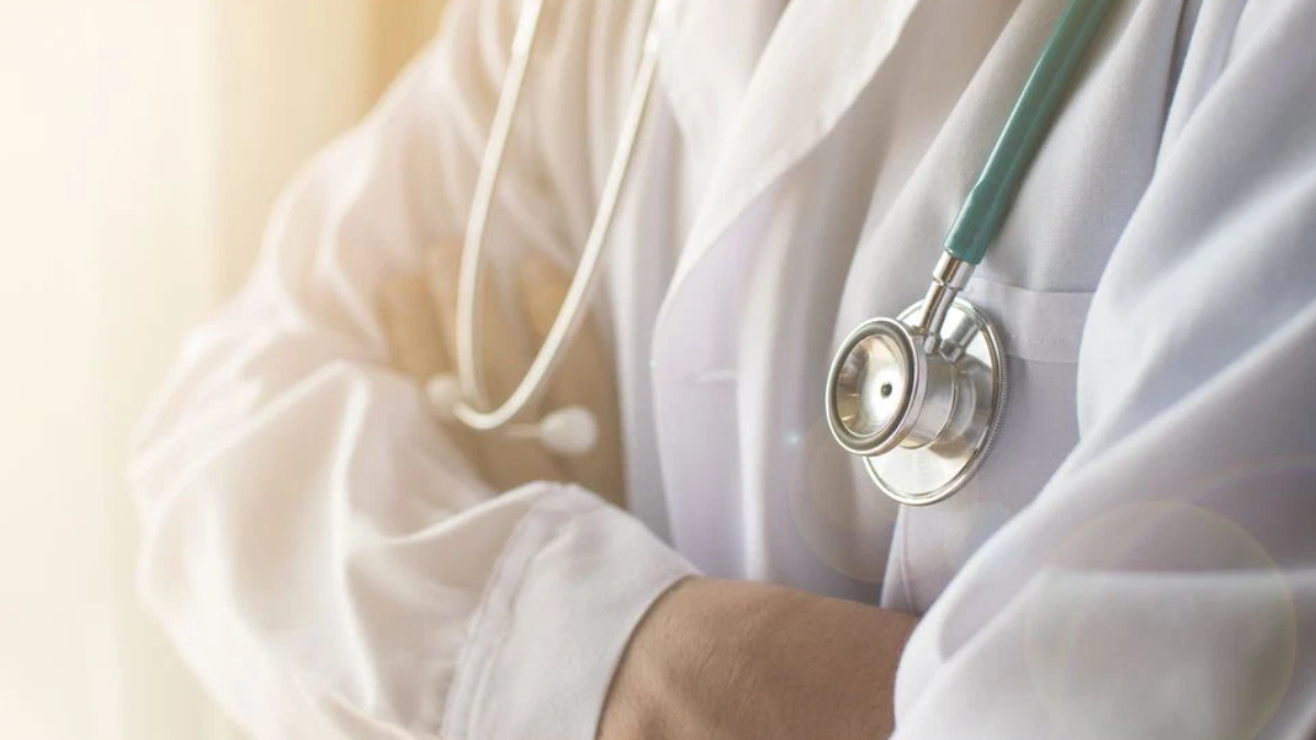 Medical professional in a white coat with a stethoscope draped around the neck, ready to examine a patient.