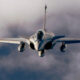 Front-on view of a fighter jet flying toward the camera through cloudy skies