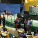 Delegates stand at podiums in the United Nations General Assembly chamber during a session.