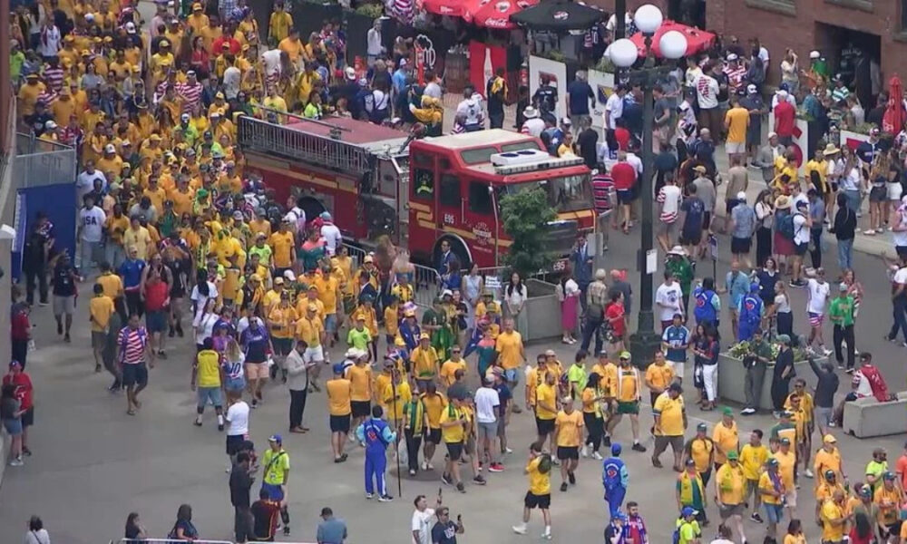Crowd of runners and spectators at a city street event, many wearing yellow shirts, with a red fire truck in the middle.