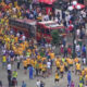 Crowd of runners and spectators at a city street event, many wearing yellow shirts, with a red fire truck in the middle.