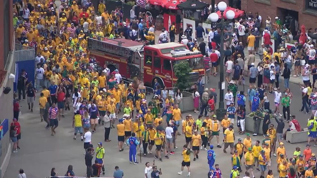 Crowd of runners and spectators at a city street event, many wearing yellow shirts, with a red fire truck in the middle.