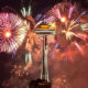 Fireworks explode around Seattle's Space Needle at night, colorful bursts lighting the sky above the city.