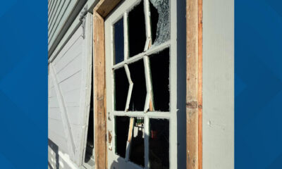 Broken window in a wooden frame of a weathered house, glass shattered and openings exposed inside the room
